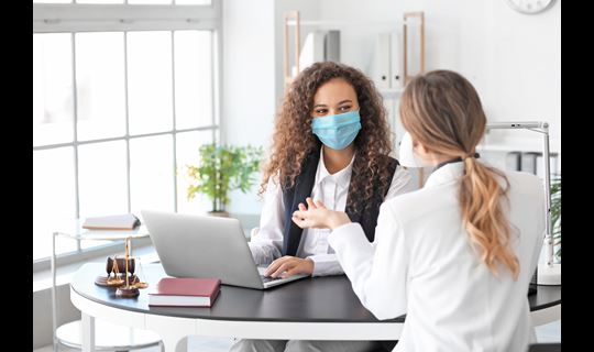 Medical staff wearing masks talking at laptop