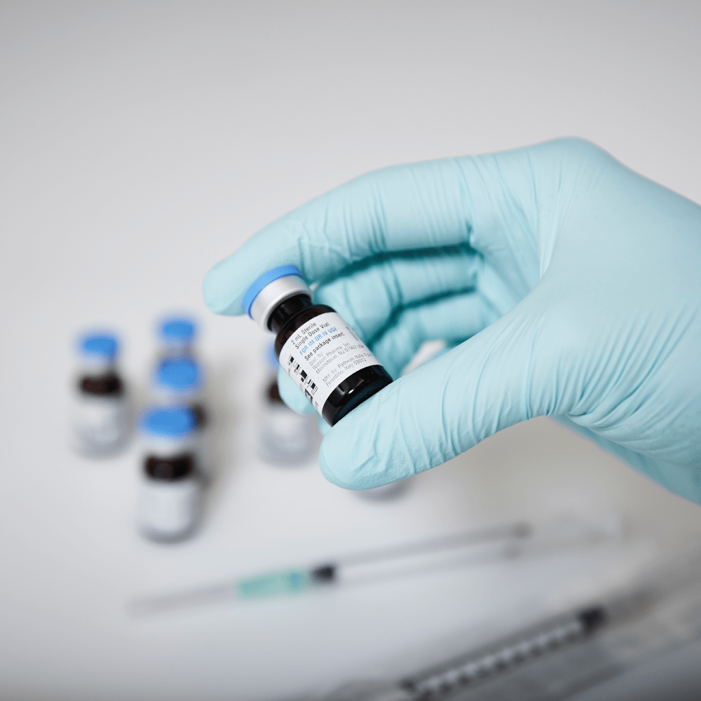 Gloved hand holding vial