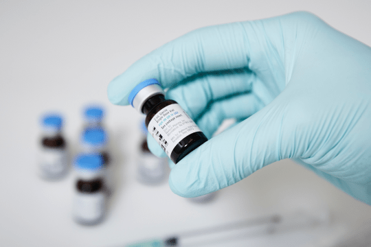 Gloved hand holding vial