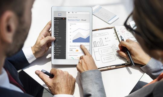 two people looking at a tablet with chart