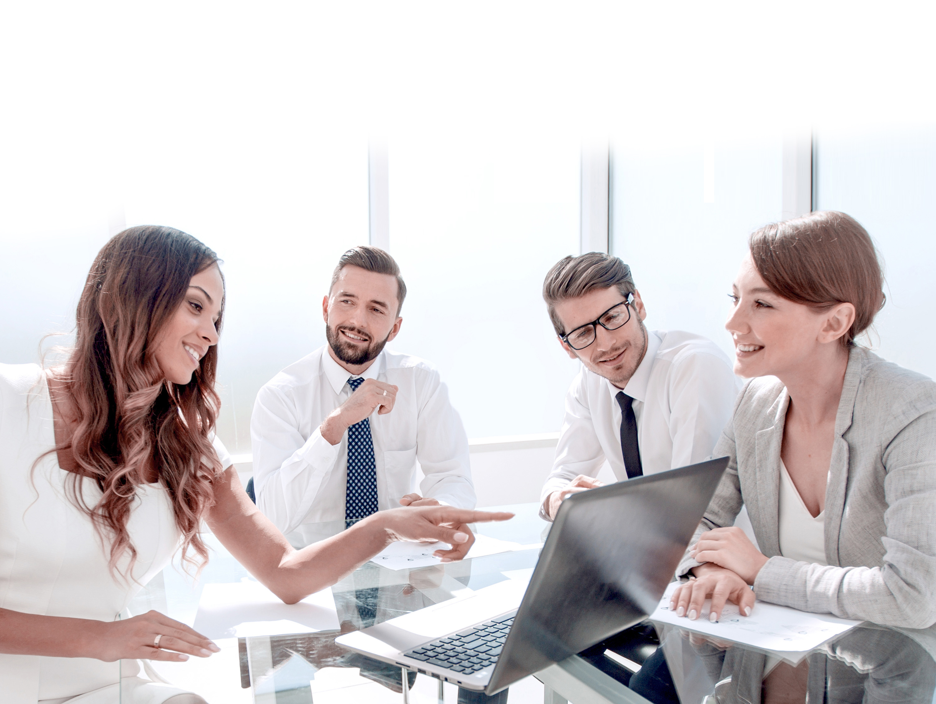 Two business women and two business men sitting around a laptop discussion the screen content